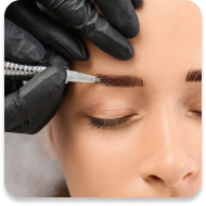 A close-up of a woman's face, focusing on her eyebrow. A gloved hand is applying a microblading technique using a tool with fine needles to enhance the appearance of the eyebrow. The woman has her eyes closed and appears relaxed. The setting suggests a professional beauty or microblading procedure.